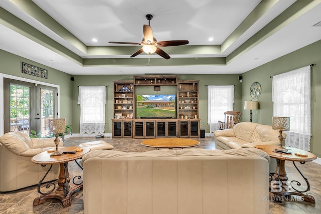 living room featuring ceiling fan, a raised ceiling, and french doors