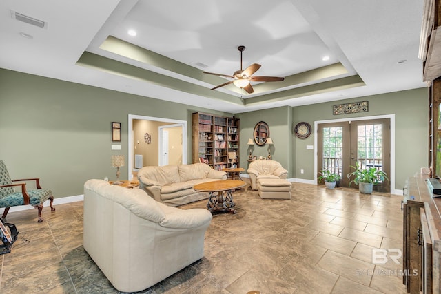 living room featuring ceiling fan, french doors, and a tray ceiling