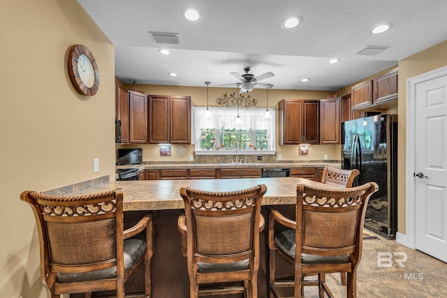 kitchen with a kitchen breakfast bar, kitchen peninsula, hanging light fixtures, and black appliances