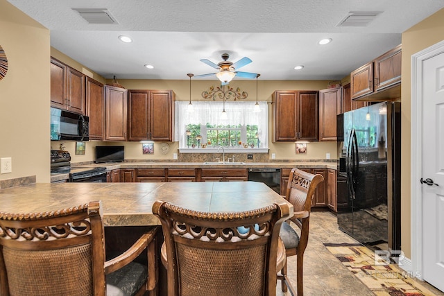 kitchen featuring black appliances, sink, hanging light fixtures, kitchen peninsula, and a breakfast bar