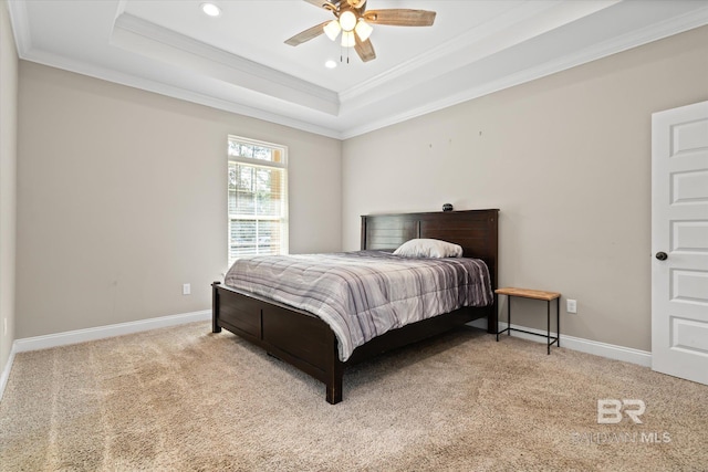 carpeted bedroom with a tray ceiling, ceiling fan, and ornamental molding