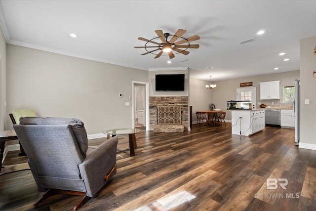 living room with ceiling fan with notable chandelier, dark hardwood / wood-style floors, crown molding, and a fireplace