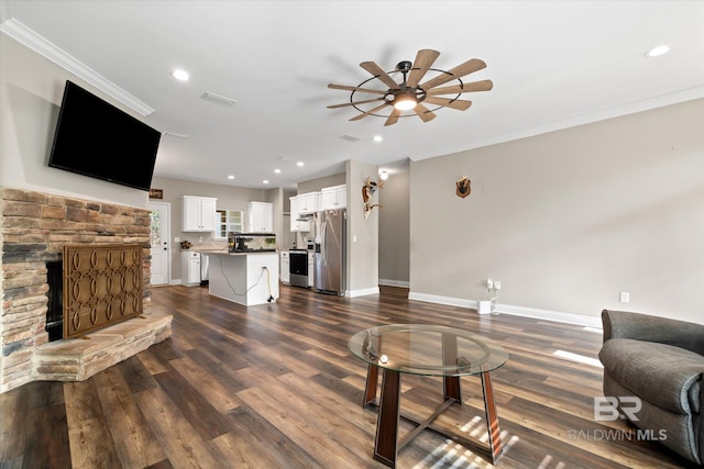 living room featuring dark hardwood / wood-style flooring, a stone fireplace, ceiling fan, and ornamental molding