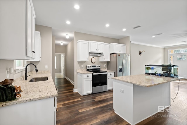 kitchen with light stone countertops, white cabinetry, sink, stainless steel appliances, and a kitchen island