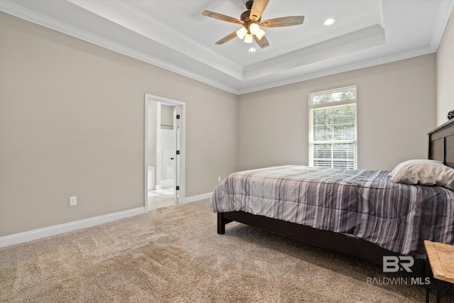 carpeted bedroom featuring ceiling fan, crown molding, a tray ceiling, and ensuite bath