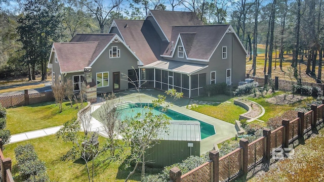 back of property featuring a sunroom, a fenced backyard, a fenced in pool, and a lawn