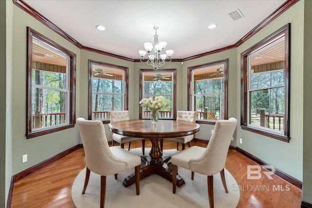 dining space with ornamental molding, light wood-type flooring, visible vents, and baseboards