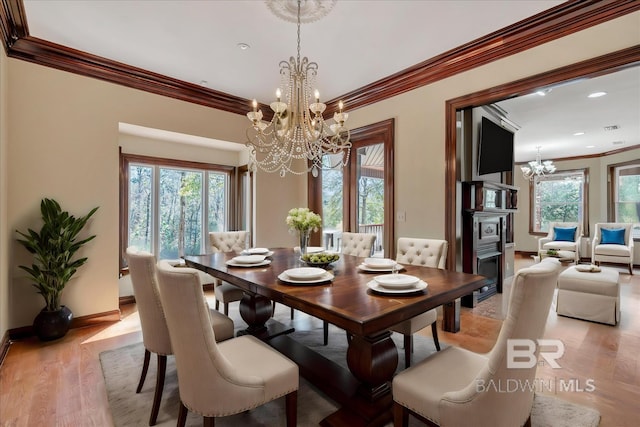 dining space with baseboards, light wood-style floors, a healthy amount of sunlight, and an inviting chandelier