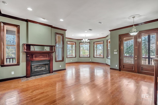 unfurnished living room featuring an inviting chandelier, a fireplace with flush hearth, plenty of natural light, and light wood finished floors