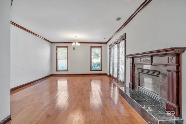 unfurnished living room with visible vents, a tiled fireplace, light wood-style floors, a chandelier, and baseboards