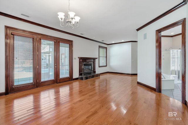 unfurnished living room with a chandelier, a premium fireplace, visible vents, baseboards, and light wood-type flooring