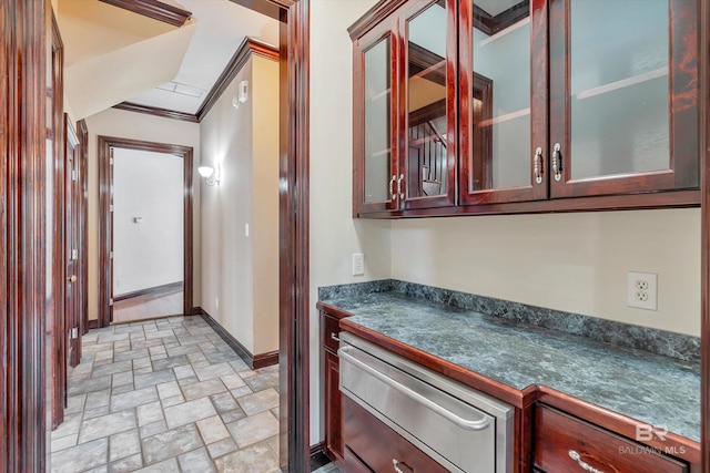 hallway featuring stone finish floor, crown molding, and baseboards