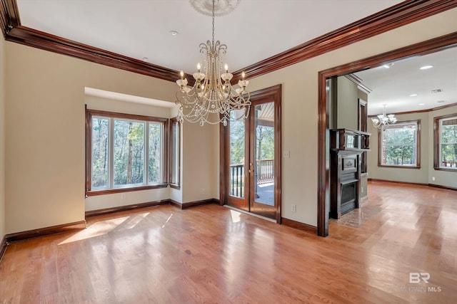 interior space with a chandelier, ornamental molding, light wood-type flooring, and baseboards