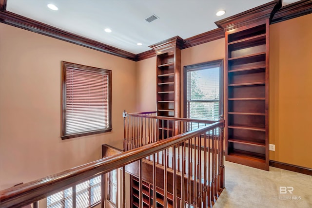 hallway with baseboards, visible vents, light colored carpet, crown molding, and an upstairs landing