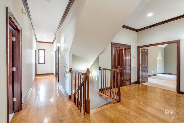 hallway featuring crown molding, light wood finished floors, an upstairs landing, and baseboards