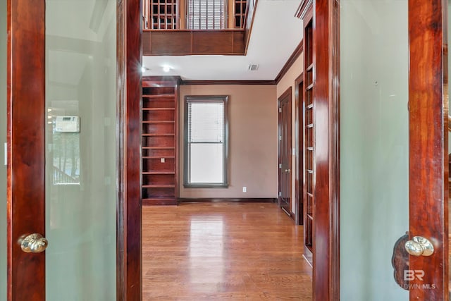 foyer entrance with ornamental molding, visible vents, baseboards, and wood finished floors