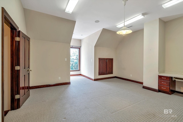 additional living space with light colored carpet, vaulted ceiling, visible vents, and baseboards