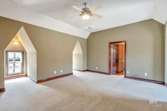 additional living space featuring light carpet, vaulted ceiling, a ceiling fan, and baseboards