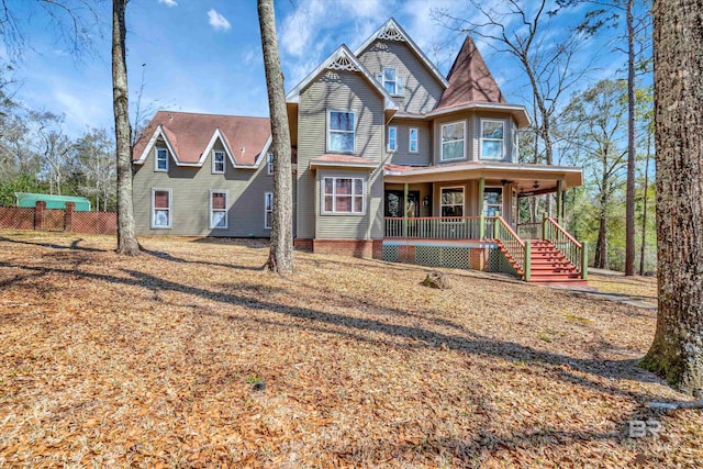 victorian home featuring a porch, fence, and stairs