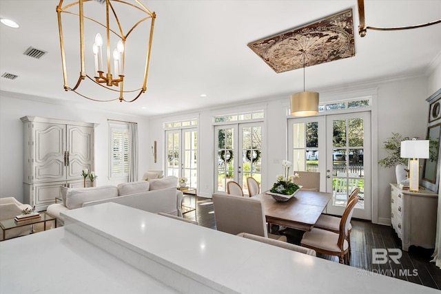 dining space with french doors, dark hardwood / wood-style flooring, an inviting chandelier, and ornamental molding