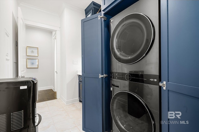 clothes washing area with stacked washer / dryer, cabinets, and ornamental molding