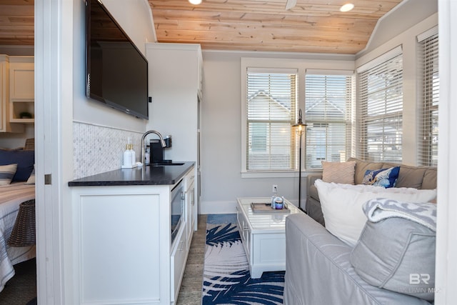 kitchen with wood ceiling, white cabinets, a sink, and open floor plan