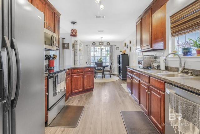 kitchen featuring sink, an inviting chandelier, appliances with stainless steel finishes, pendant lighting, and light hardwood / wood-style floors