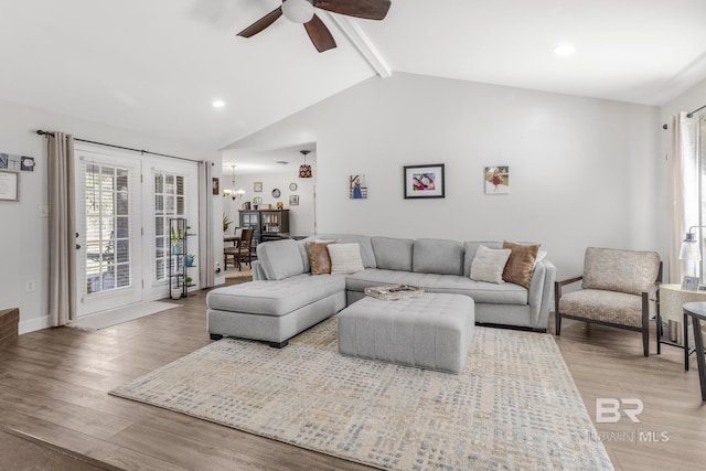 living room with ceiling fan with notable chandelier, light hardwood / wood-style floors, and vaulted ceiling with beams