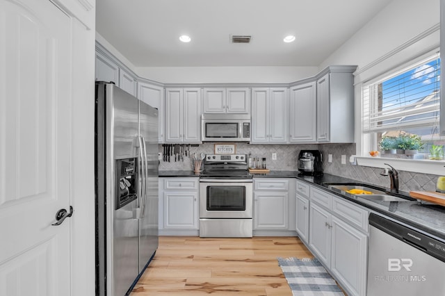 8847 Asphodel Ln, Daphne, AL 36526 - kitchen with stainless steel appliances, a sink, dark countertops, light wood-type flooring, and recessed lighting