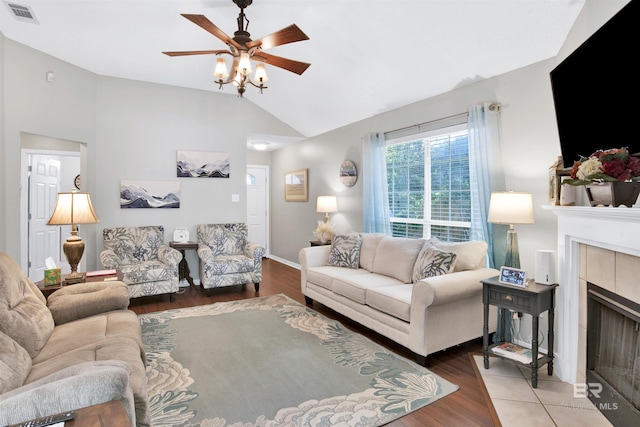 living area featuring visible vents, wood finished floors, a fireplace, and vaulted ceiling