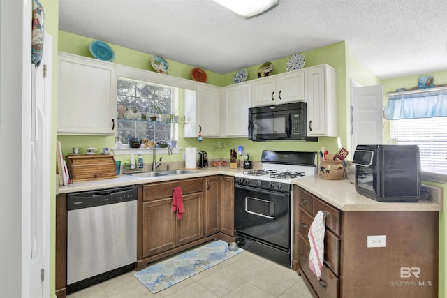 kitchen featuring a sink, stainless steel dishwasher, range with gas cooktop, black microwave, and light countertops