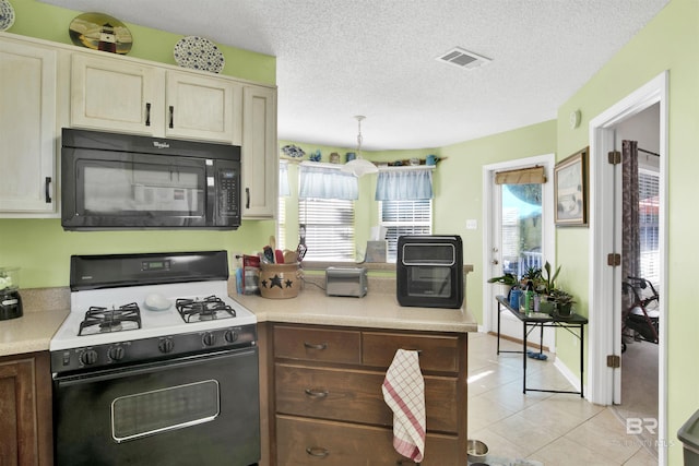 kitchen with visible vents, range with gas cooktop, black microwave, light countertops, and light tile patterned floors