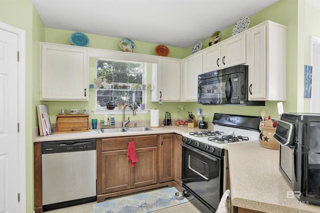 kitchen featuring black microwave, gas range, light countertops, stainless steel dishwasher, and a sink