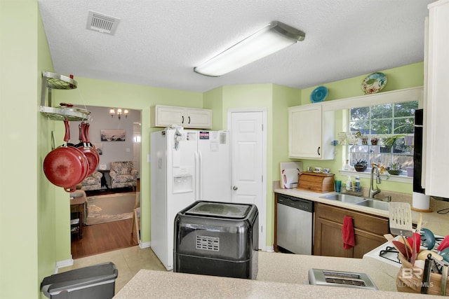 kitchen with visible vents, a sink, stainless steel dishwasher, a textured ceiling, and light countertops