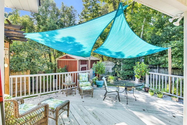 deck with outdoor dining area, a storage shed, a fenced backyard, and an outdoor structure