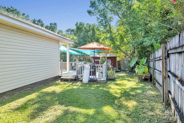 view of yard with an outbuilding, a fenced backyard, a shed, and a wooden deck