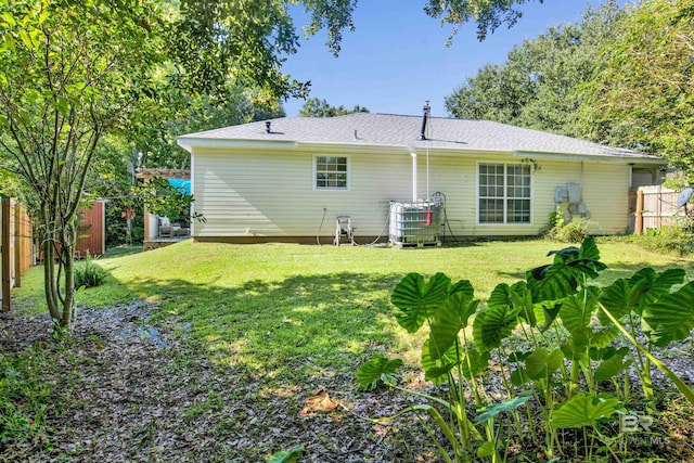 rear view of house featuring a yard, central AC unit, and fence