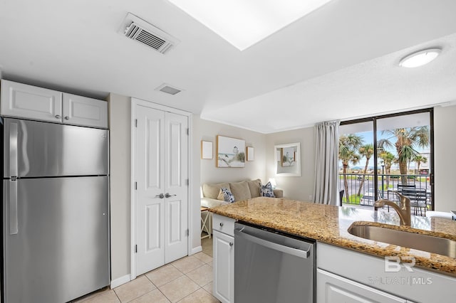 kitchen featuring light stone countertops, appliances with stainless steel finishes, white cabinetry, sink, and light tile patterned floors