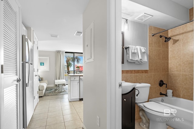 full bathroom with toilet, tiled shower / bath, tile walls, tile patterned floors, and vanity