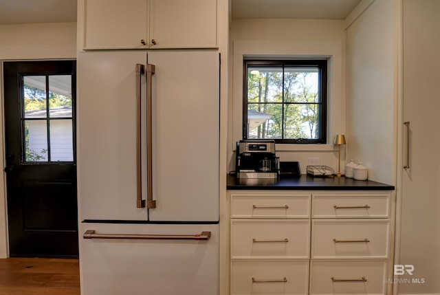 kitchen with high end fridge, white cabinetry, plenty of natural light, and wood-type flooring