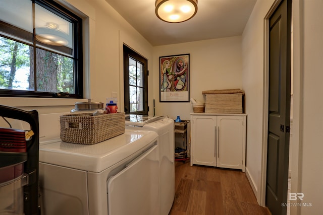 laundry room with washer and clothes dryer, hardwood / wood-style flooring, cabinets, and a healthy amount of sunlight