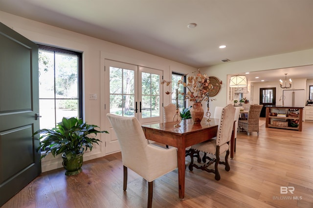 dining room featuring light wood-type flooring, a chandelier, and french doors