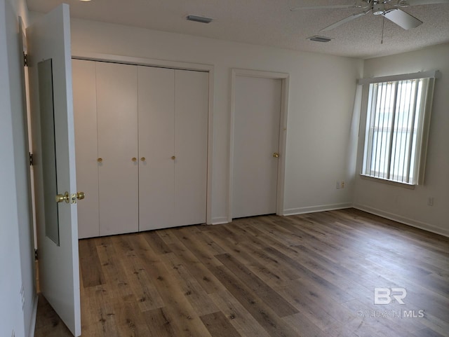 unfurnished bedroom featuring wood finished floors, visible vents, a ceiling fan, a closet, and a textured ceiling