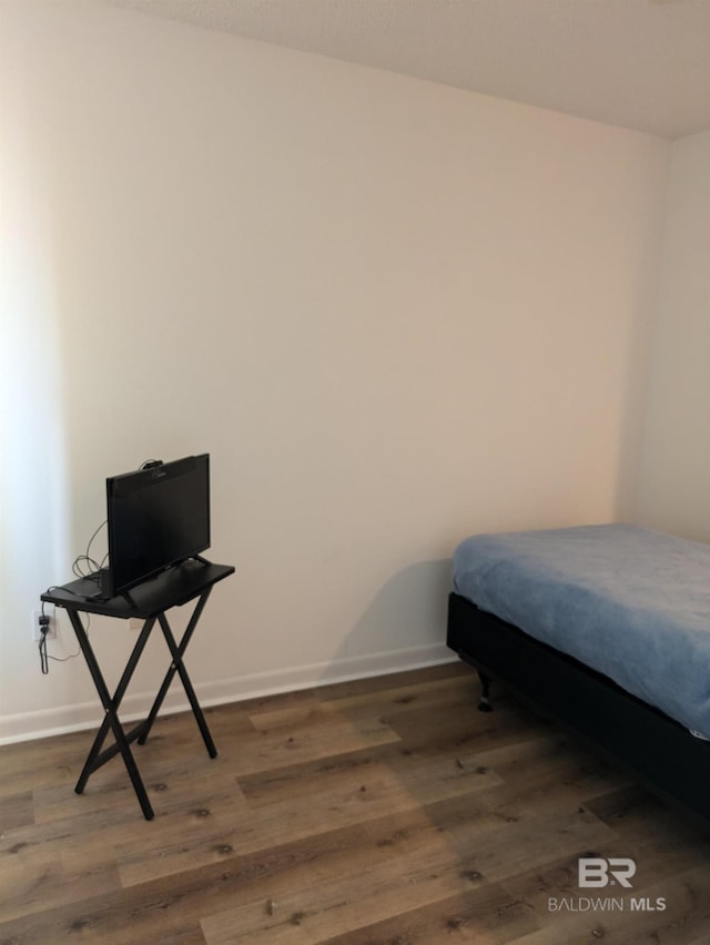 bedroom featuring baseboards and wood finished floors