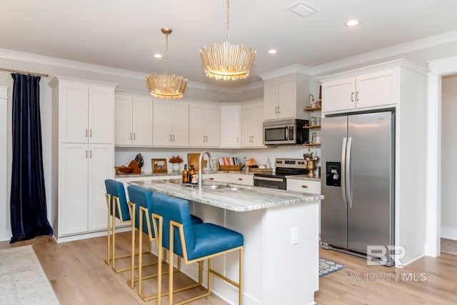 7339 Grissom Dr, Saraland, AL 36571 - kitchen with stainless steel appliances, white cabinetry, light wood finished floors, a sink, and decorative light fixtures