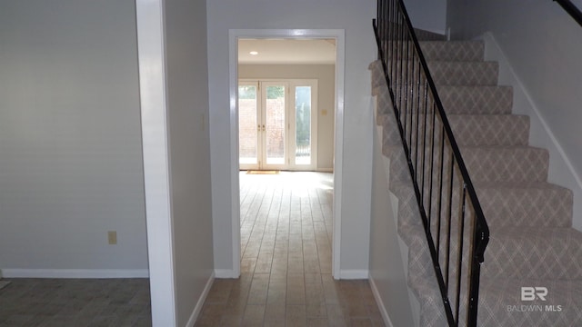 stairway with hardwood / wood-style floors and french doors