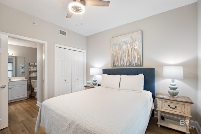 bedroom with wood finished floors, baseboards, visible vents, a closet, and connected bathroom