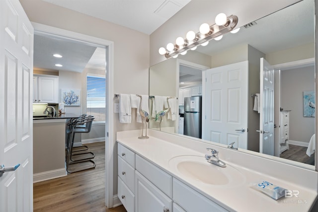 bathroom featuring vanity, wood finished floors, visible vents, and baseboards