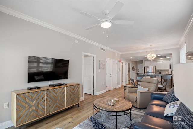 living area featuring baseboards, visible vents, light wood finished floors, ornamental molding, and ceiling fan with notable chandelier