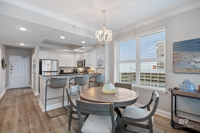 dining room featuring an inviting chandelier, baseboards, light wood-type flooring, and ornamental molding